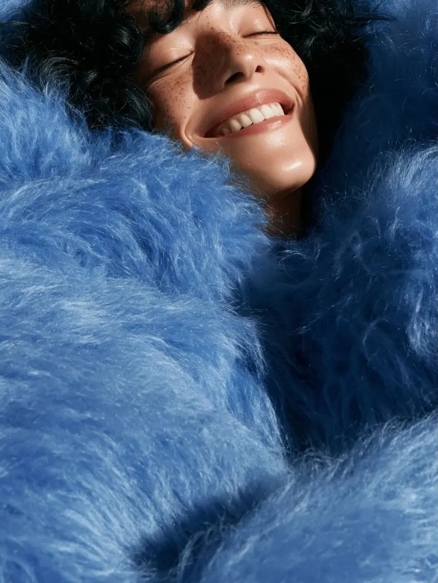 Portrait of a laughing woman wrapped in electric blue fur